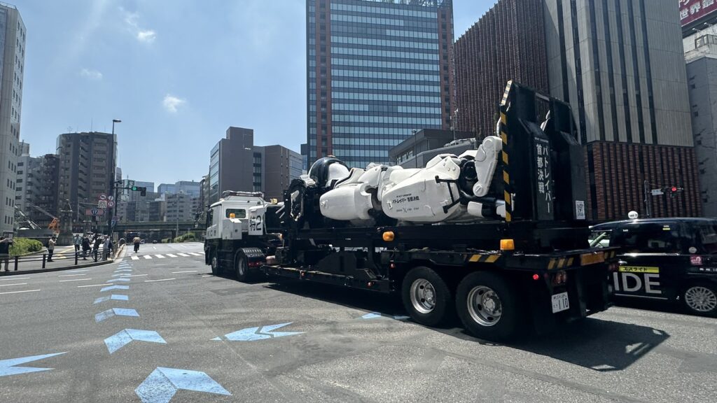 秋葉原を走るKC庁トラックに積まれたパトレイバー風の白い機体